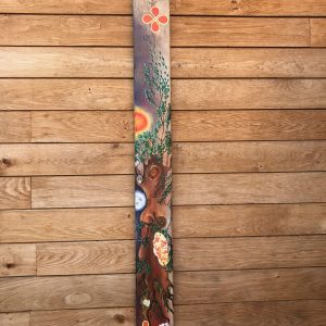 Long piece of driftwood with leaves and flowers painted on it to represent happiness