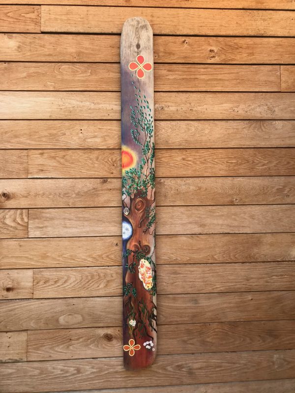 Long piece of driftwood with leaves and flowers painted on it to represent happiness