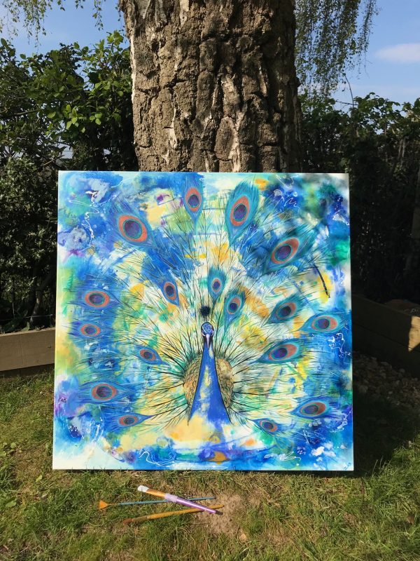 peacock in blues and greens on a square canvas leaning against a tree
